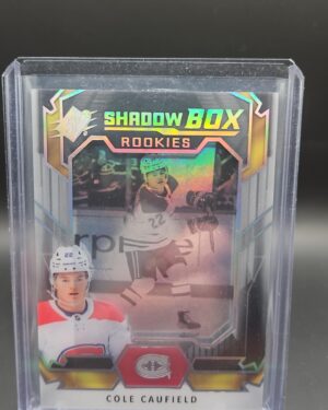 2021-22 Upper Deck SPx Shadow Box Rookies Cole Caufield #SB-1 rookie card, featuring a premium multi-layered acetate design and dynamic Montreal Canadiens graphics from the SPx set.