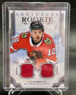 2017-18 Upper Deck Artifacts Rookie Dual Jersey /399 card #III featuring Alex DeBrincat of the Chicago Blackhawks, a premium memorabilia rookie card highly sought after by NHL collectors.