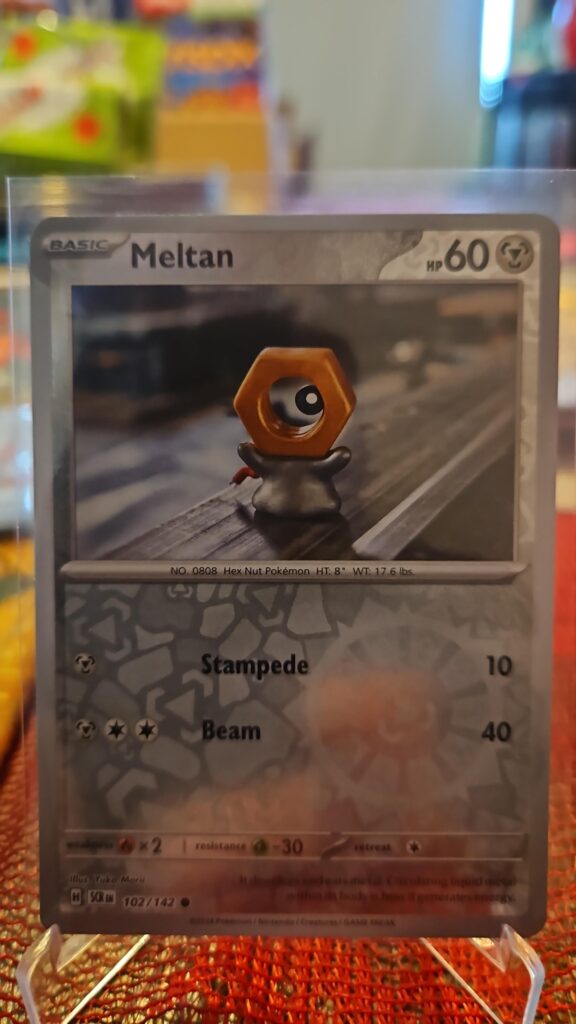 2024 Meltan 102/142 Reverse Holo Pokémon card from Stellar Crown displayed in Near Mint condition.